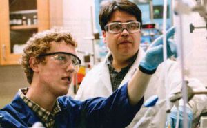 Two scientists wearing protective goggles in a lab. 