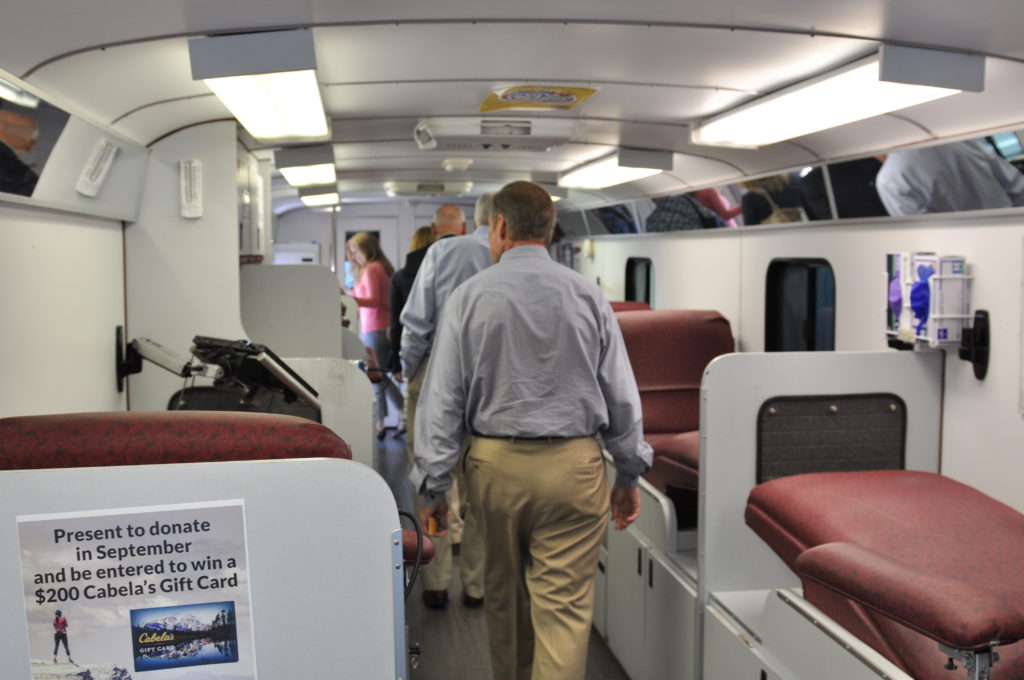 A group of adults inside a bloodmobile, a large bus for receiving blood donations. 