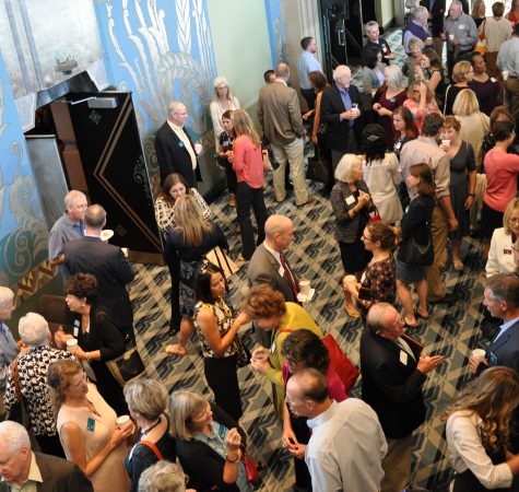 An overhead shot of a room of adults mingling in a historic theater.