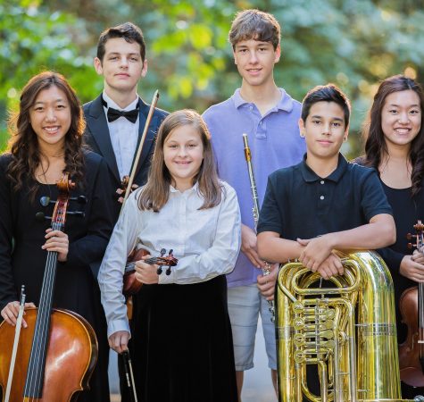Five young musicians pose for the camera outside while holding their instruments.