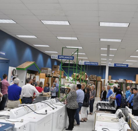 A group of people on a tour of the Habitat for Humanity store facilities, with appliances and supplies throughout the store.