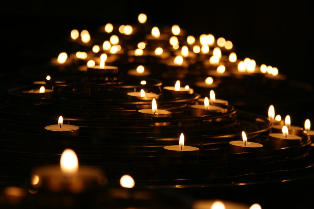 Many candles on a stand, shining bright in the dark. 
