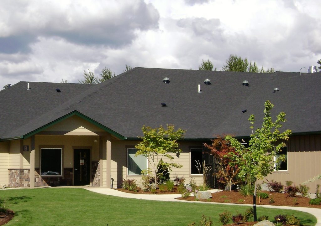 An outdoor shot of the Kairos Northwest Facility, which has tan walls and a brown roof. 