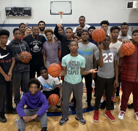 A group of Black teens and mentors pose for a photo on a basketball court