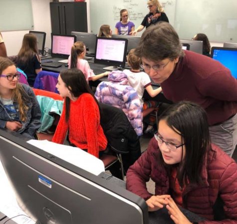 A female teacher helps a female student in a computer lab
