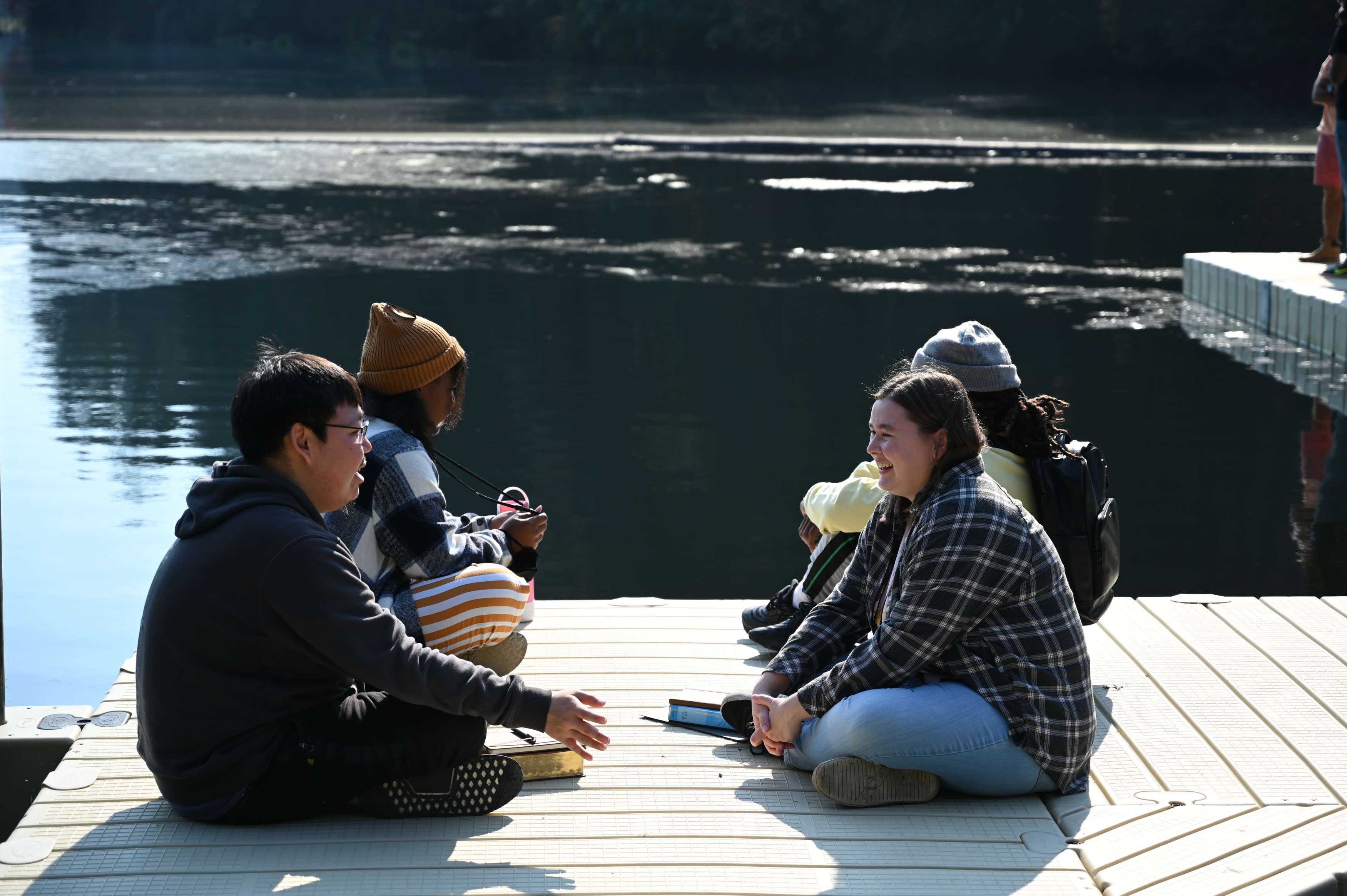 Four students have a conversation on a dock by a lake at the Vision & Call 2022 retreat.