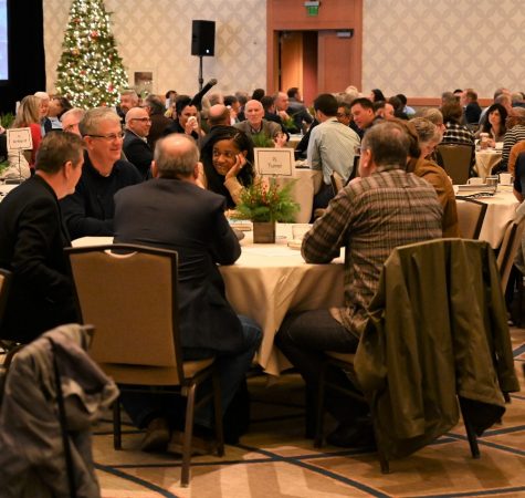 A group of participants at the Leadership Now 2022 conference chat around a table, with a Christmas tree in the background. 