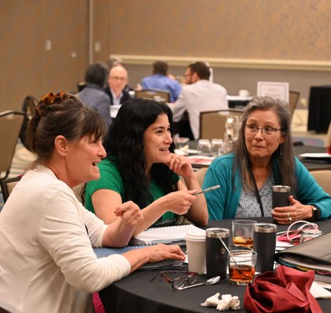 Three women have a conversation at a table at the Board Leadership conference
