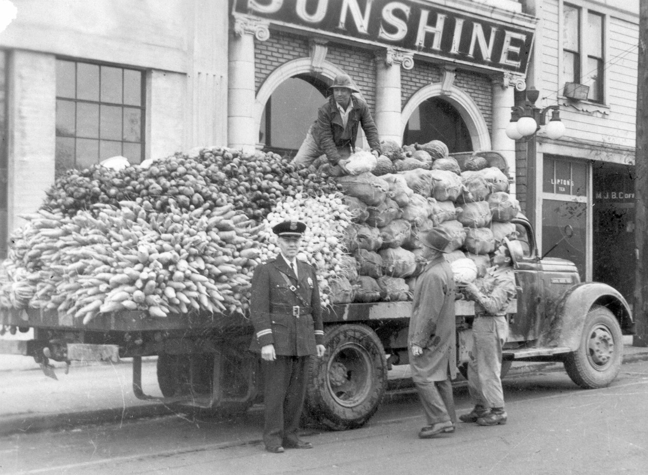 A black and white photo of a group of men loading food onto a truck in Portland, Oregon.
