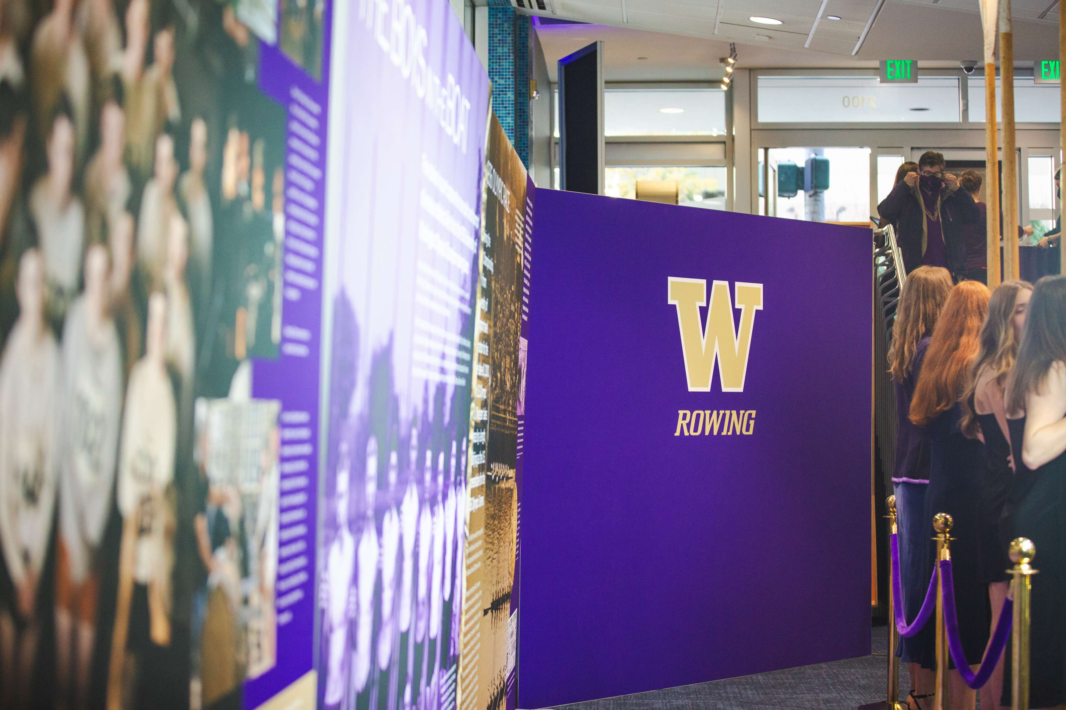 A purple sign that says "W Rowing" with a queue line next to it.