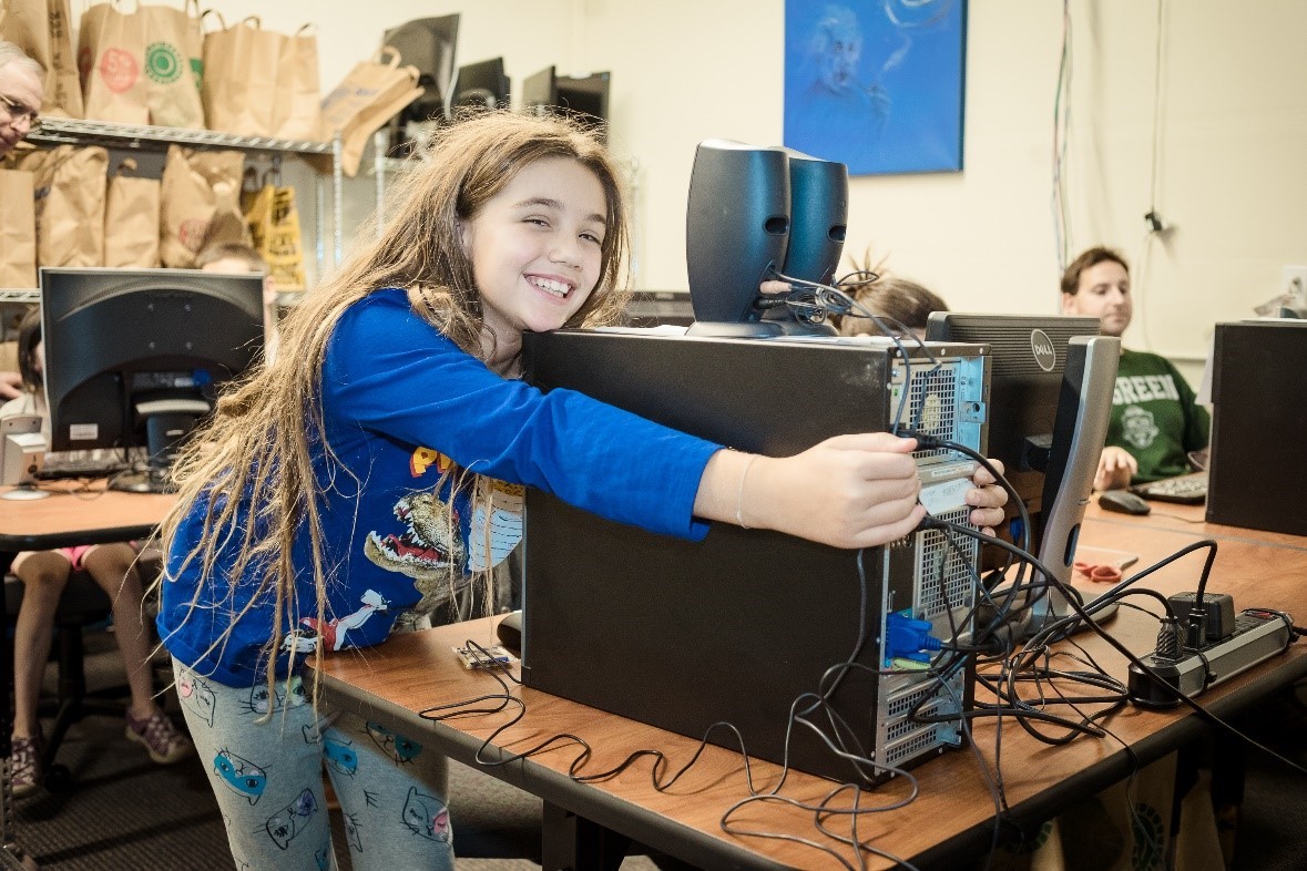 Child smiling and hugging a computer, receiving tech education