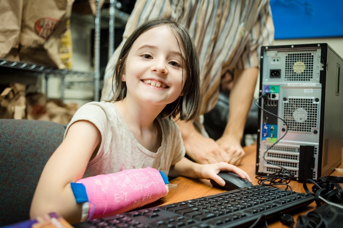 Girl with arm in a cast using a computer and smiling 