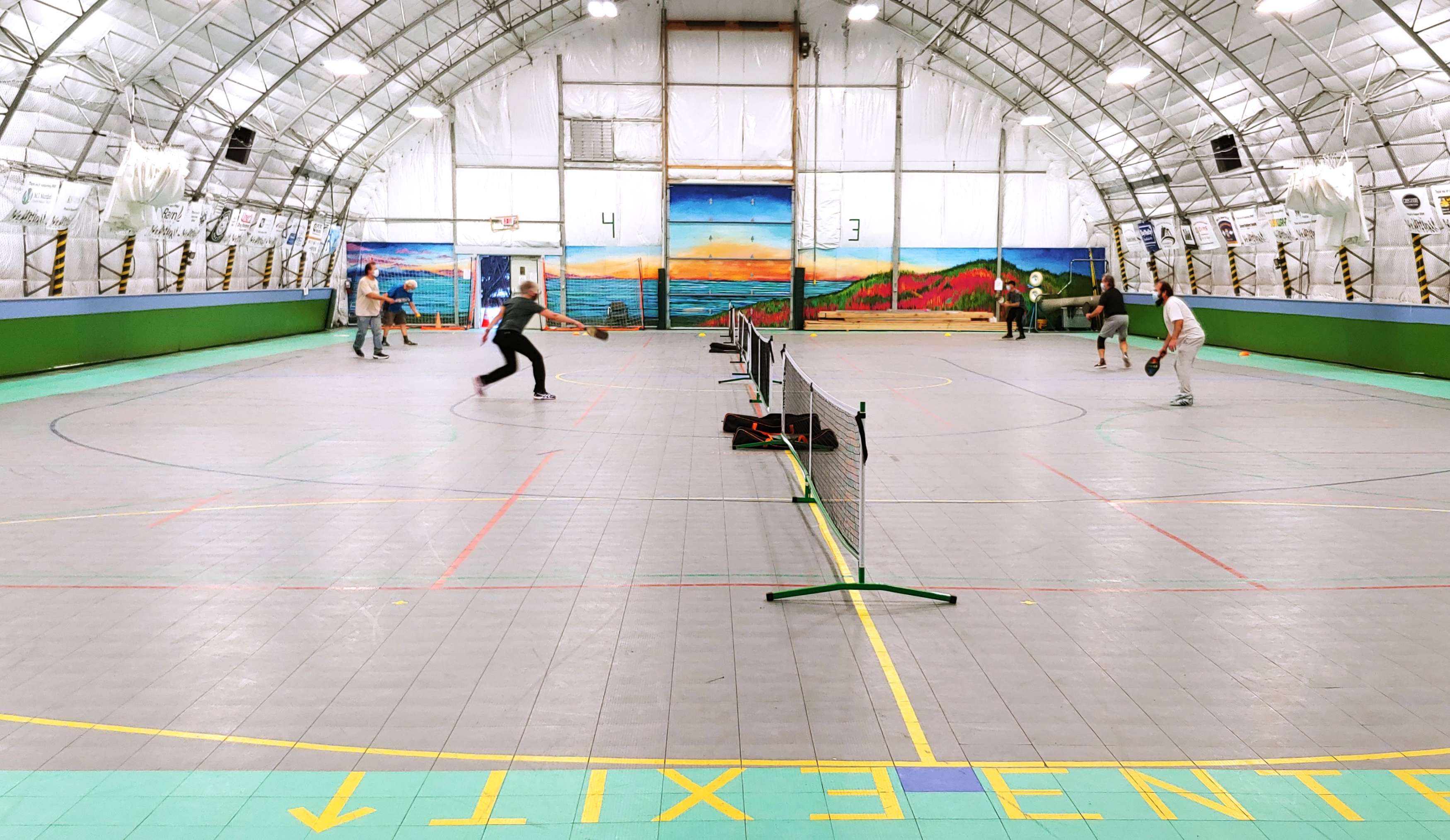 3 groups of adults playing pickleball on an indoor court