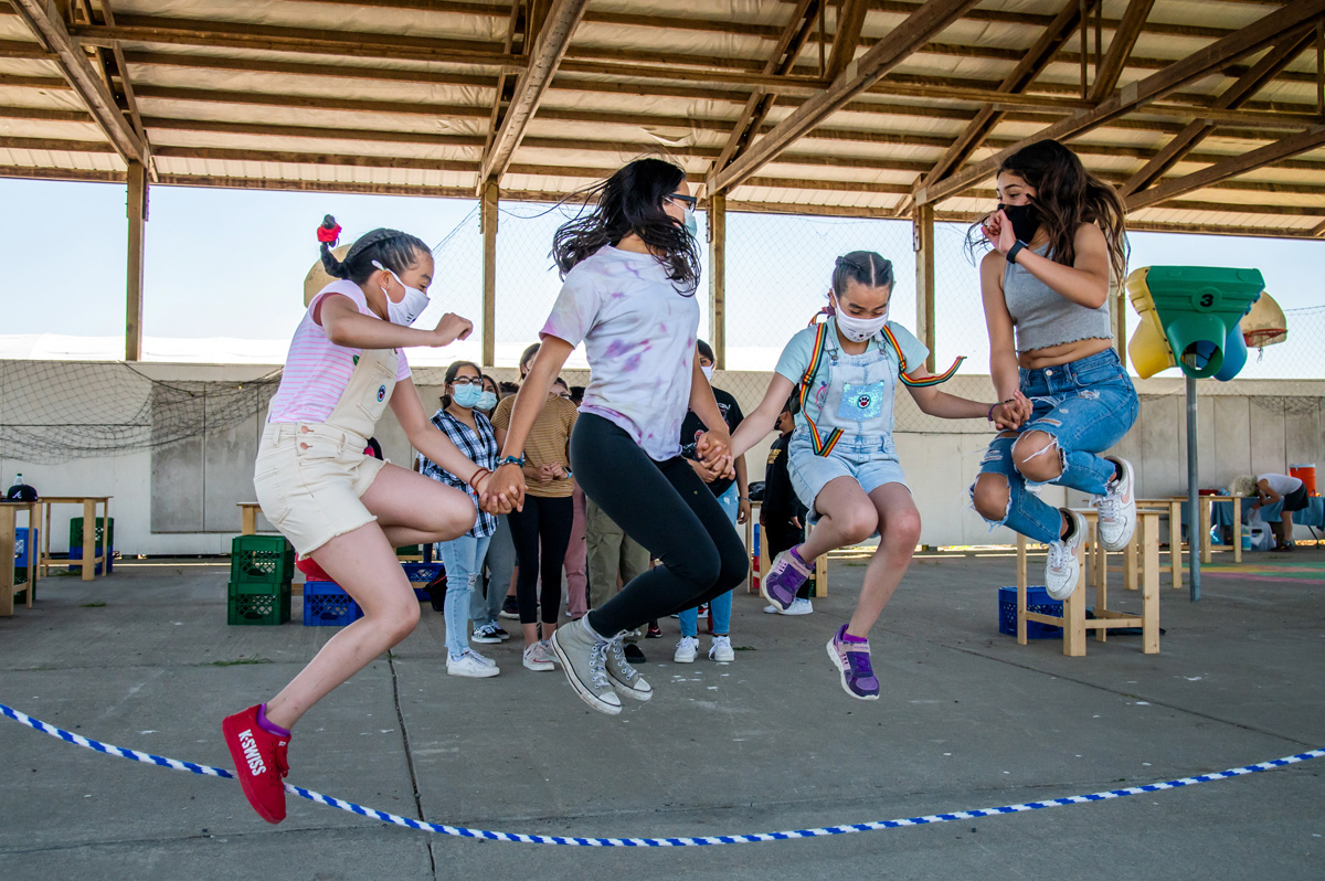 Four young girls holding hands and jumping rope together