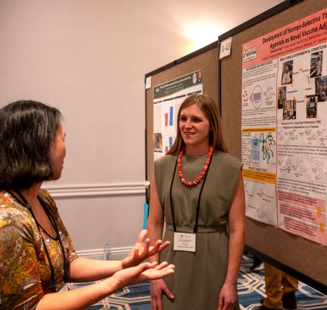 Teacher presenting science research to a conference participant 