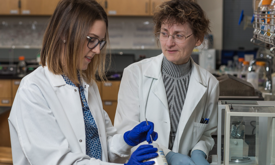 Instructor and student in white lab coats and plastic gloves