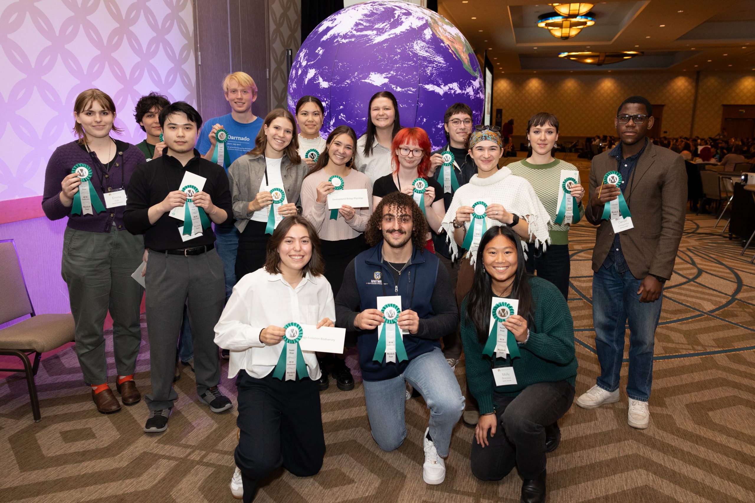 students kneeling and standing together, holding up their awards and smiling