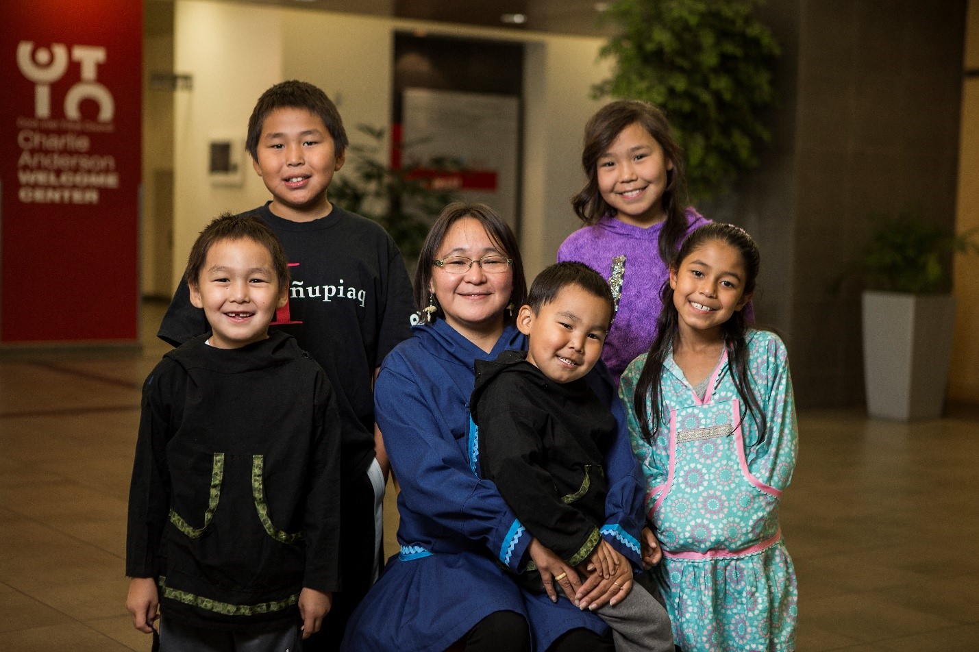 Adult with five children on and around them smiling