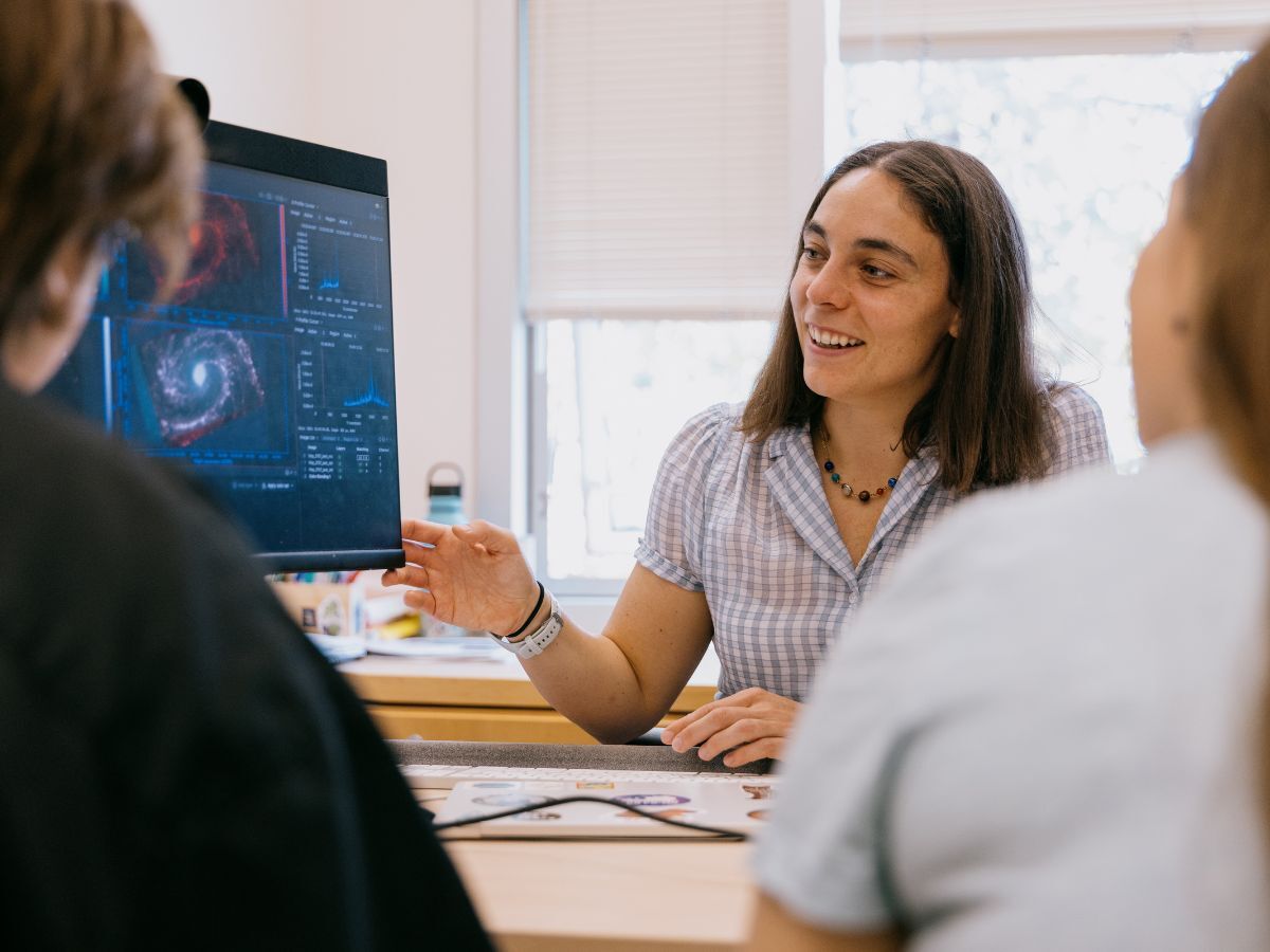 Jessica Sutter, a professor at Whitman College, shows galaxy photos to two students on her computer.