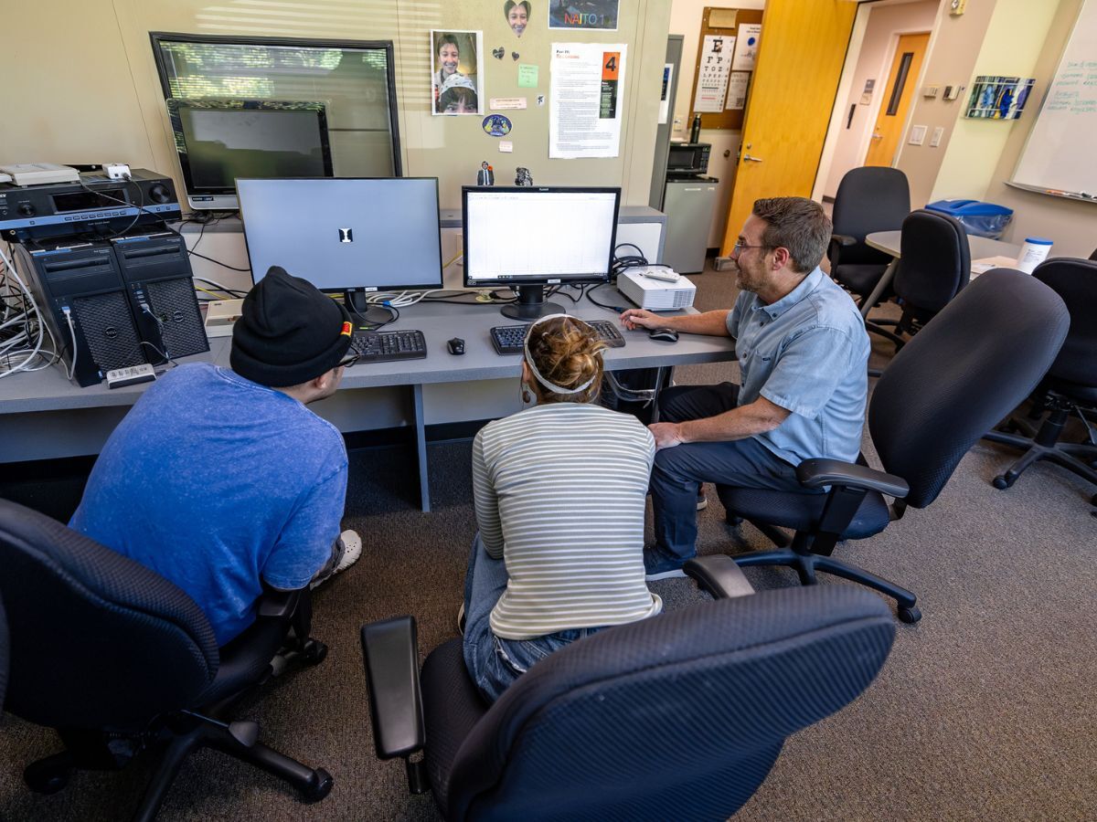 Michael Pitts, professor of psychology at Reed College, showing two students research on a computer screen