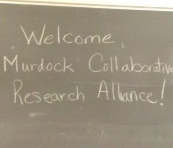 A chalkboard with "Welcome, Murdock Collaborative Research Alliance" written on it.