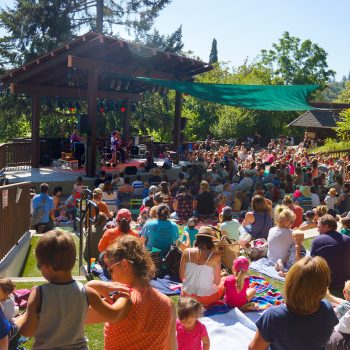 Families gather on picnic blankets in an outdoor amphitheater.