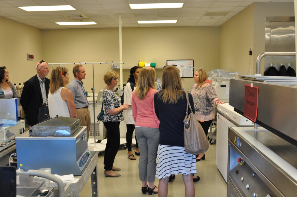 A group of adults inside a blood donation facility, getting a tour from a staff member.