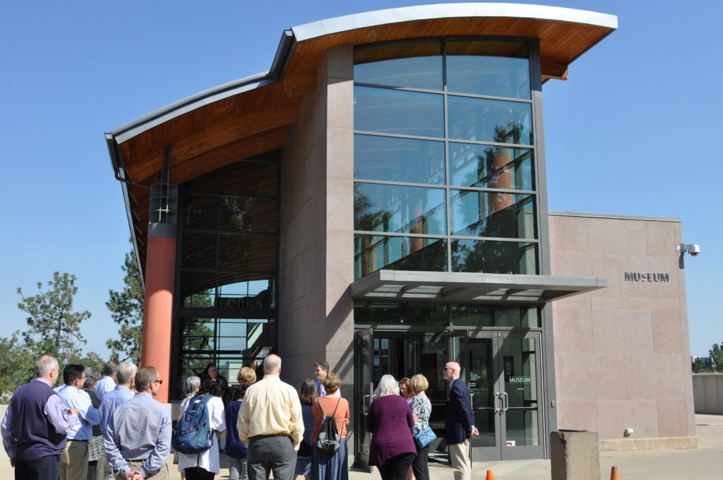 A group of people gathered outside the entrance to a large building labeled "Museum."