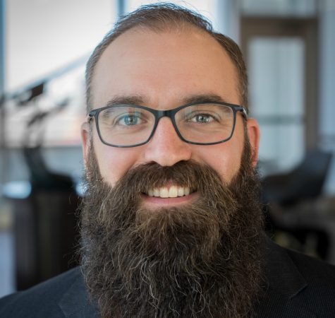 A man with a beard and glasses smiling at the camera.