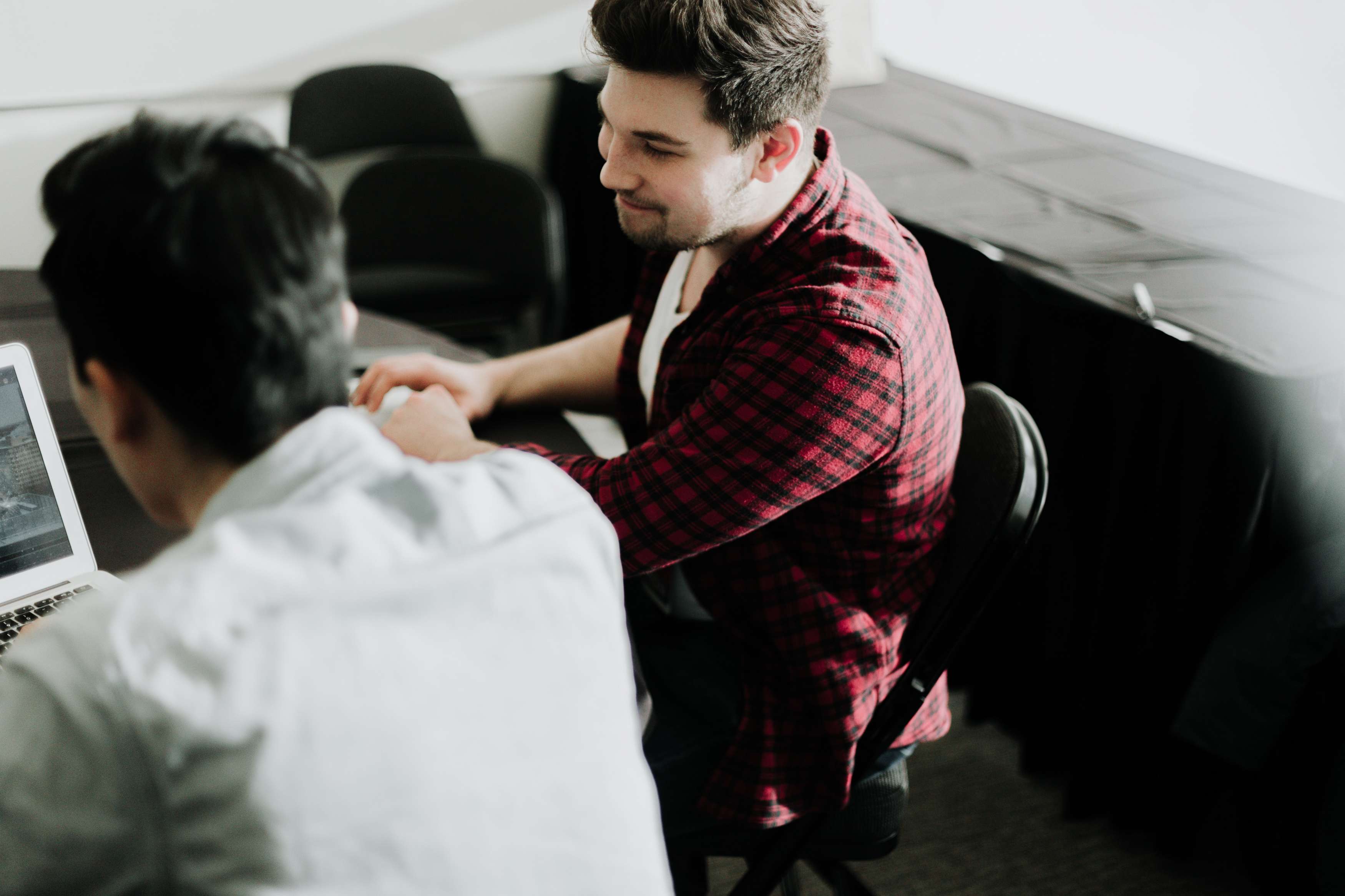 An overhead shot of two men sitting at a table working on laptops.