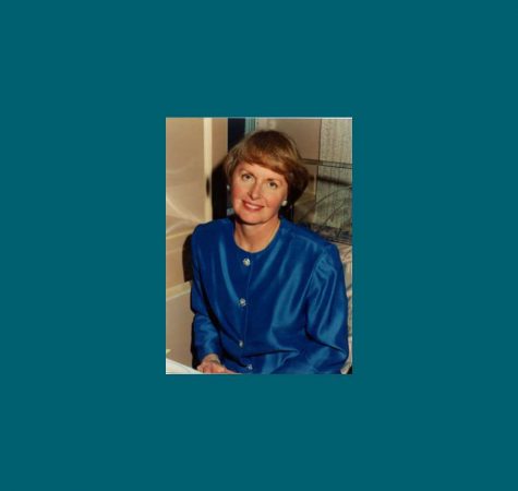 A woman with brown hair wearing a blue shirt smiles for the camera.