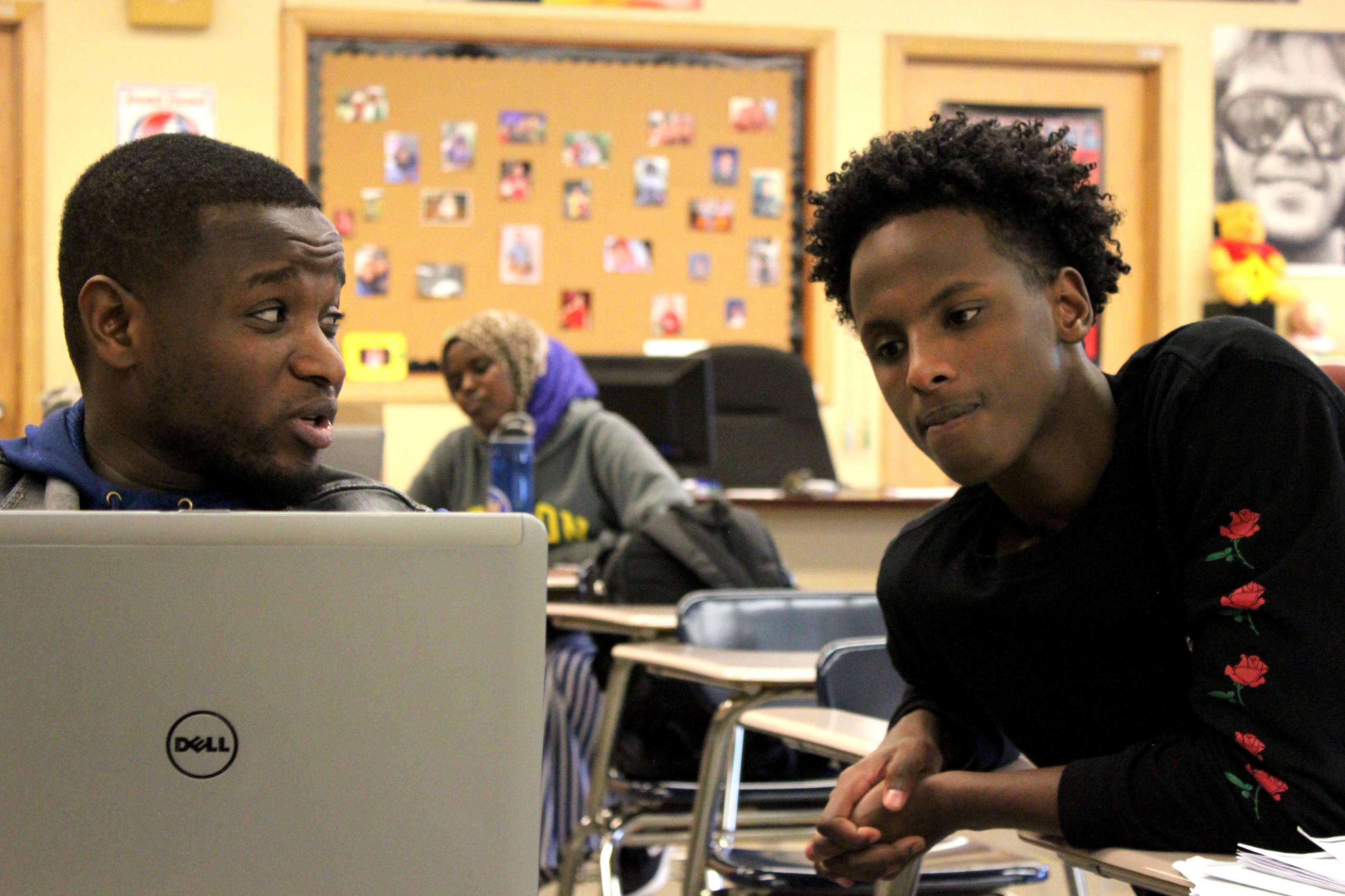 A man teaches a teen on a computer