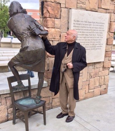 Man standing next to bronze statue of Anne Frank