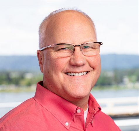 Dana Miller, a man wearing a pink shirt and glasses, smiles for the camera.