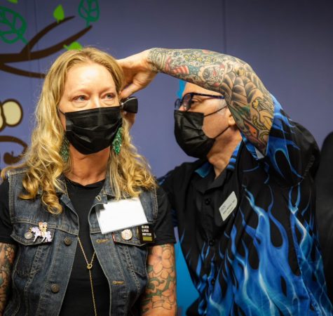 A woman wearing a face mask gets her ears checked.