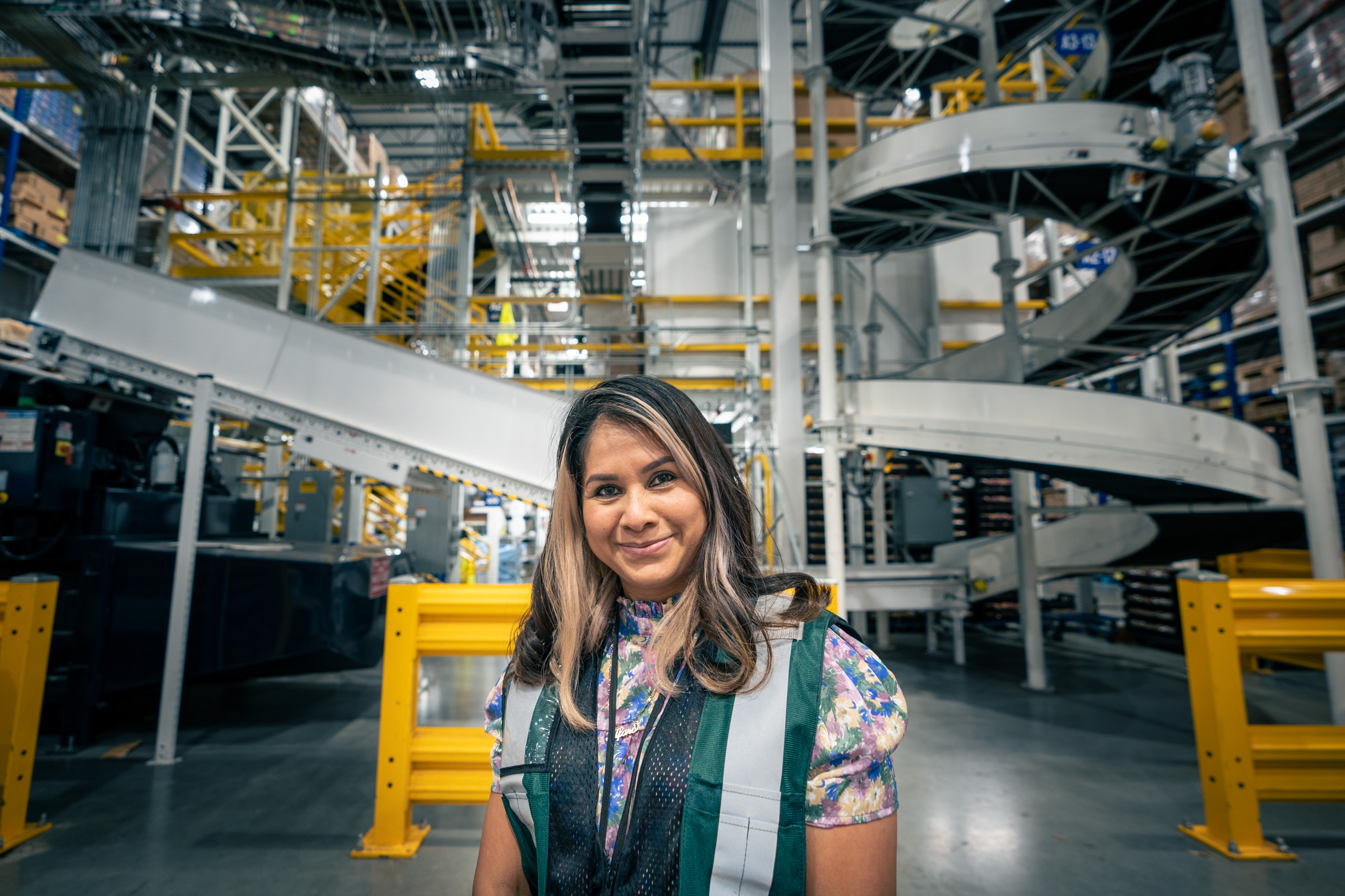 A woman smiles for the camera while standing in a factory.