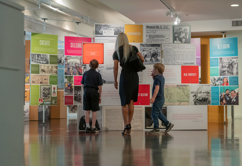 Two children and a young woman look through exhibits at the OJMCHE.