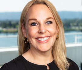 A woman with blond hair wearing a black shirt smiles for the camera.