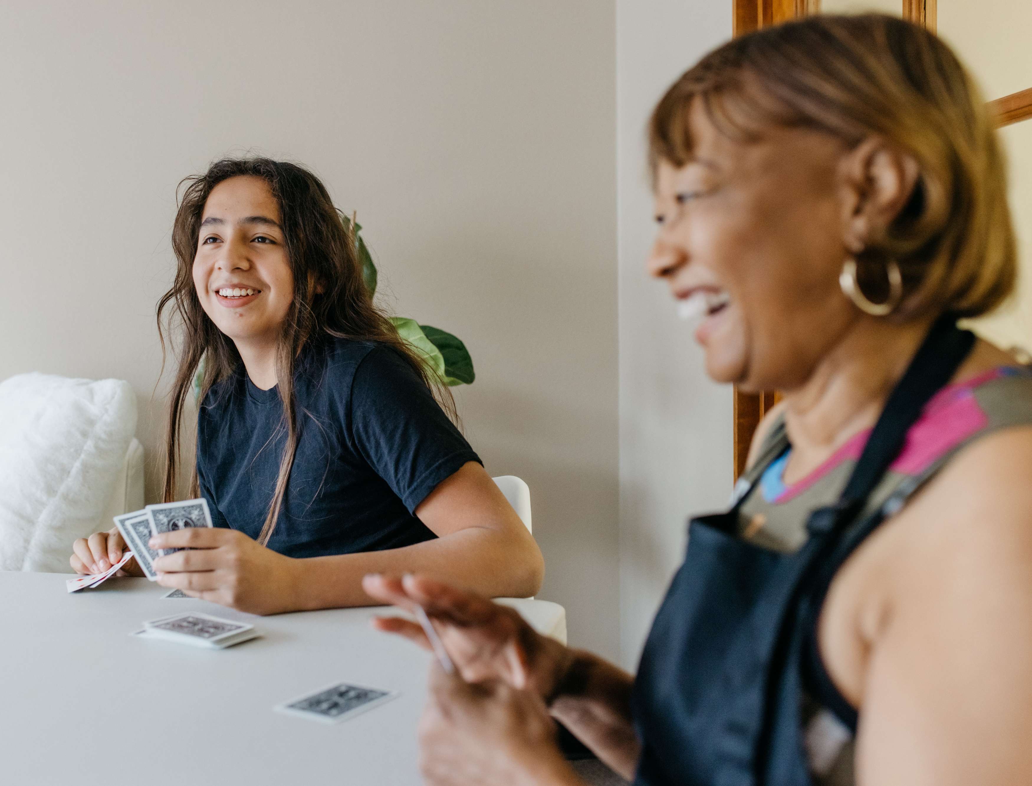 Young male playing cards and smiling with laughing older woman