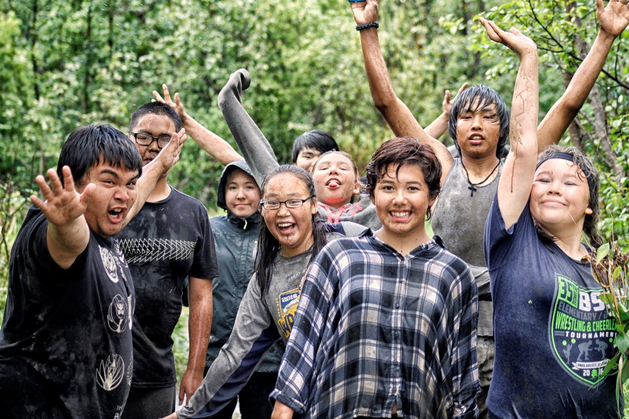 Group of children smiling triumphantly, doused with mud