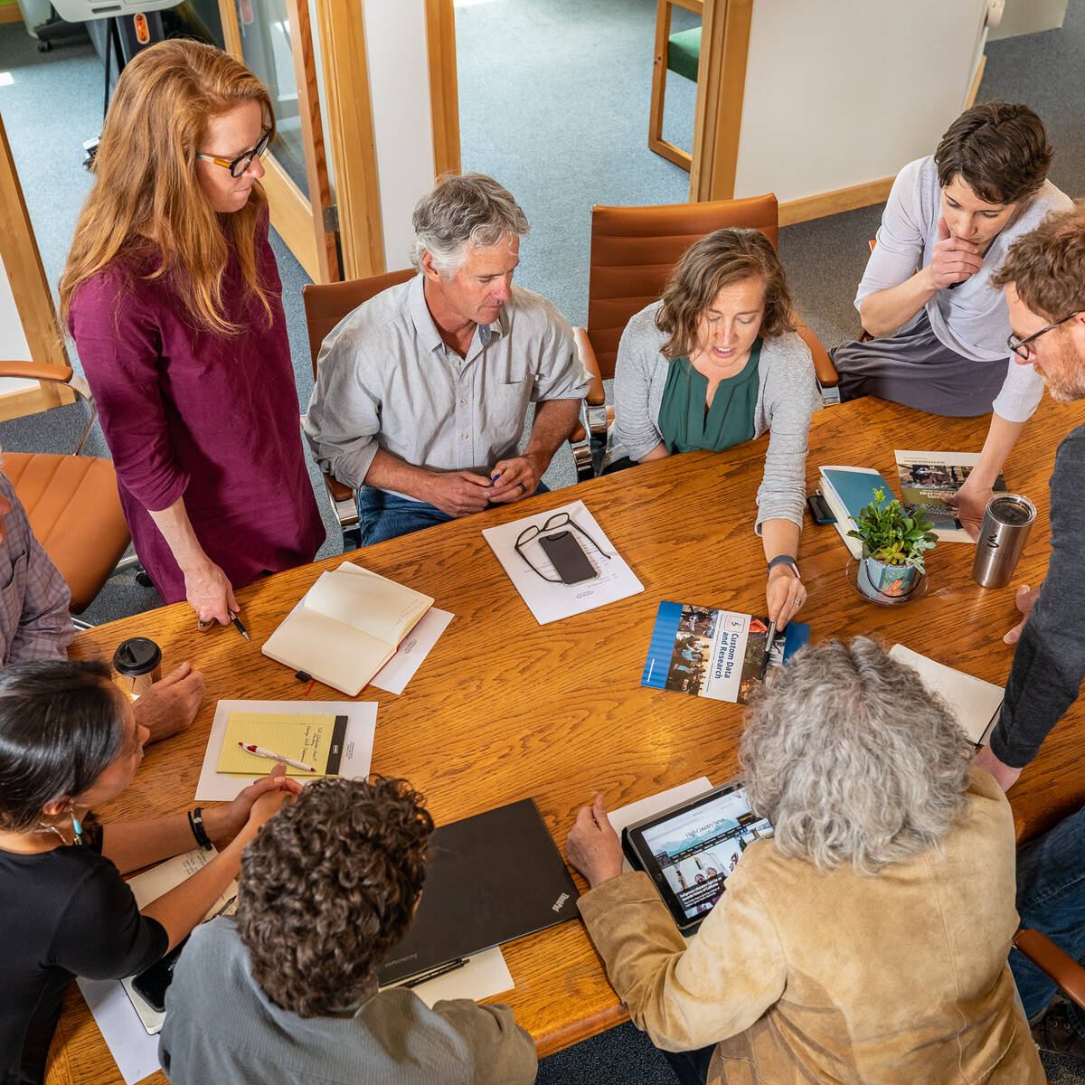 Montana nonprofit leaders sitting and standing around a table with pamphlets and notebooks
