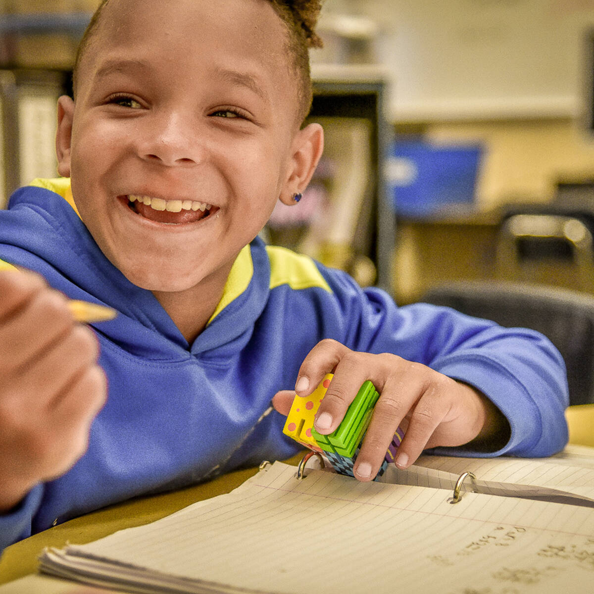 Young student smiling with a pencil in one hand and binder open